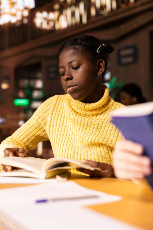 Young girl scholar reading and taking notes in a library